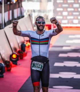 Man wearing Scooby tri suit crossing Ironman finish line