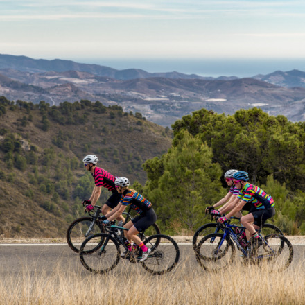 four cyclists riding against a mountainous backdrop