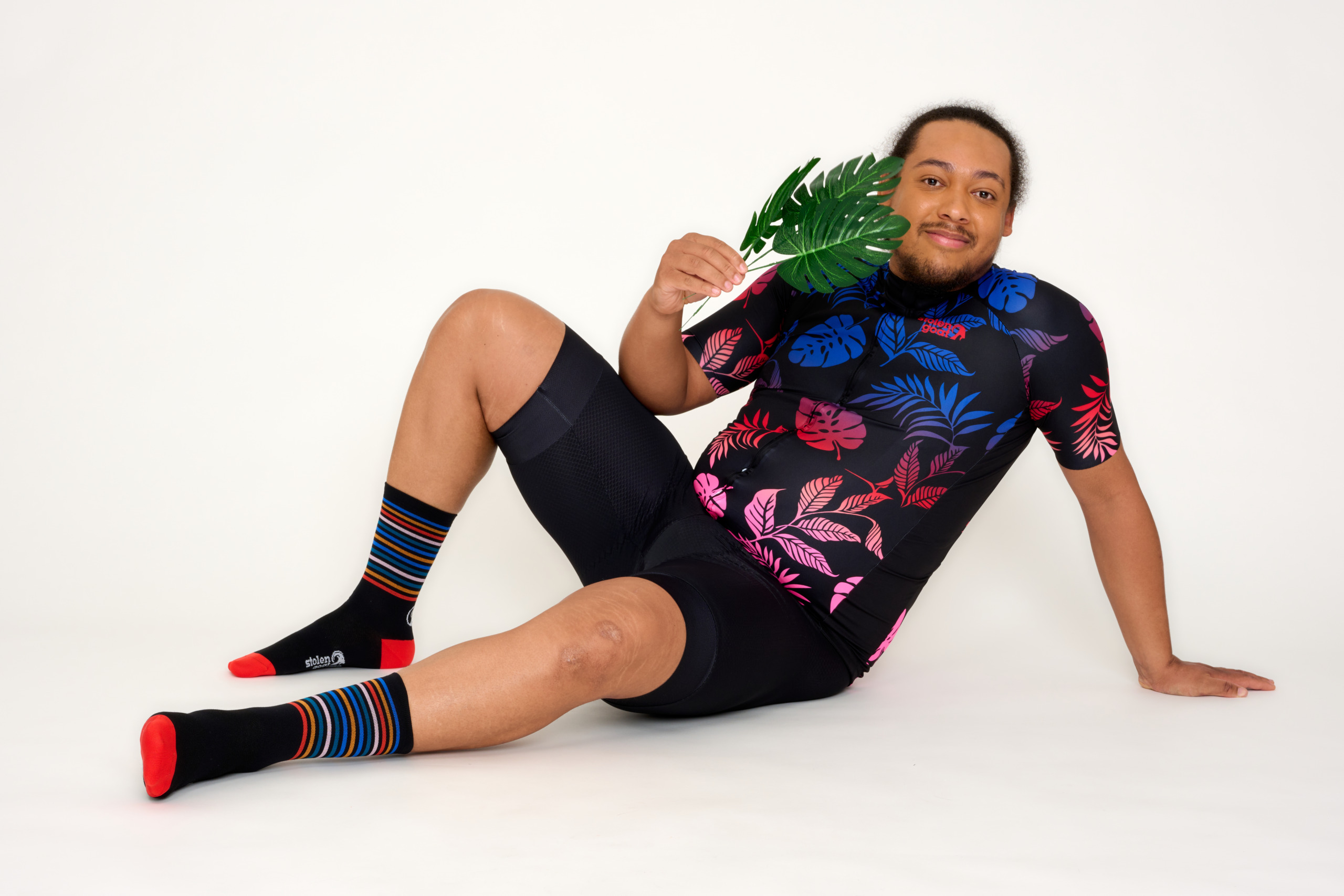 man in cycling kit with palm leaves sitting on floor