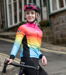 Female cyclist wearing Cortez jersey leaning on her bike on a street