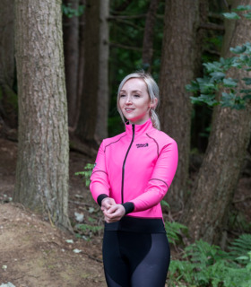 Woman wearing Stolen Goat Alpine Epic pink jacket facing camera adjusting sleeves
