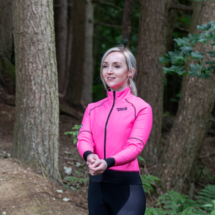 Woman wearing Stolen Goat Alpine Epic pink jacket facing camera adjusting sleeves