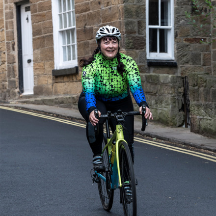 Woman cycling down a hill wearing the Noodles jersey