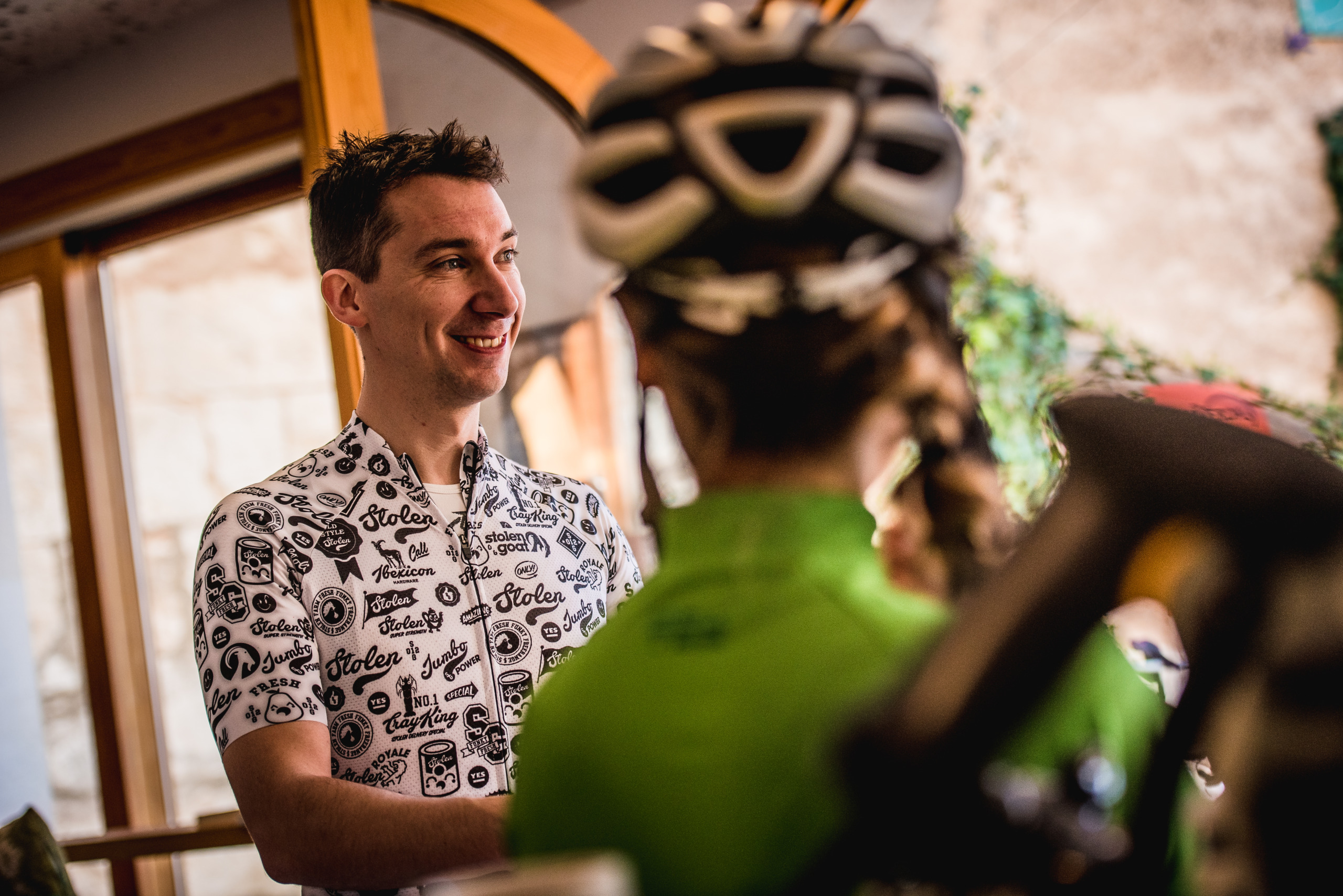 SG CEO and Founder Tim Bland talking to cyclists wearing black and white scribble print Stolen Goat jersey