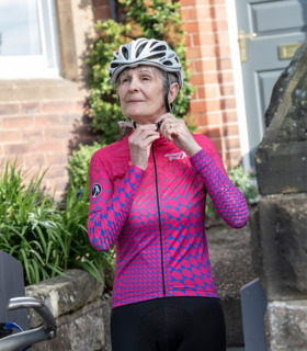 Woman wearing Sane jersey outside a house doing her cycling helmet up