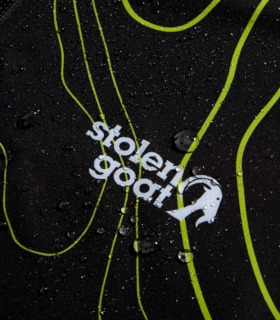 Close up of white stolen goat logo on women's enduro mtb jacket with water droplets to demonstrate product's water resistance.