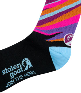 Close up of Stolen Goat Sliver socks, black foot section with blue heel, blue stolen goat logo and slogan on the sole and graphic pink, purple, orange and blue design on the ankle.