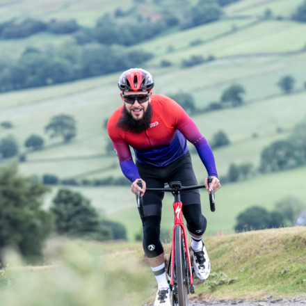 Man wearing Ibex Argyle jersey cycling up a hill