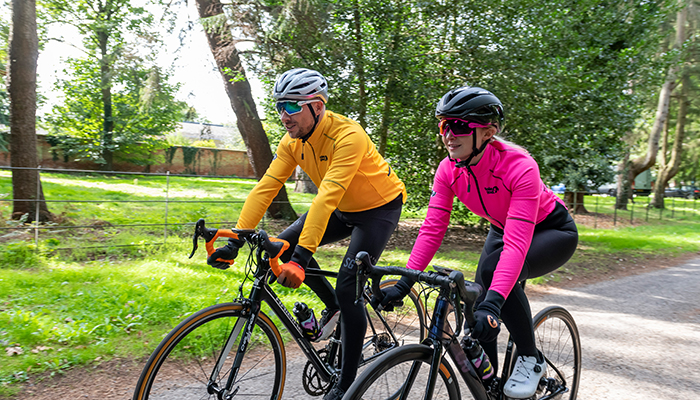 man and woman riding bikes wearing mango and pink alpine epic jackets