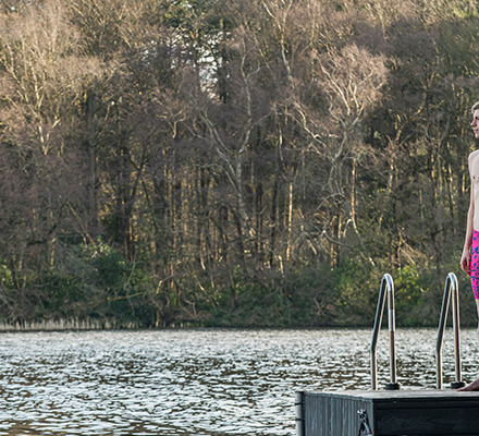 man standing next to a lake wearing upstart swim jammers