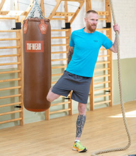Man warming up in the gym before a run wearing the blue short sleeved running top