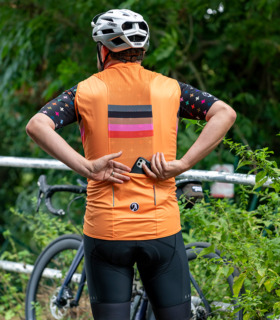 Man wearing orange and block stripe Quadrant gilet with his back to the camera, putting his phone in the central rear pocket