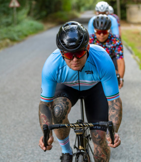 Man riding his bike down on the drops wearing men's Turin Ibex Epic jersey blue with retro central block stripe