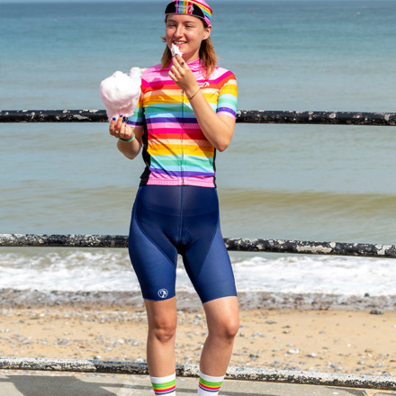 Woman eating candyfloss at the beach wearing the pink stripe Arcadia jersey