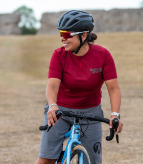 Woman on a gravel bike wearing maroon gravel jersey