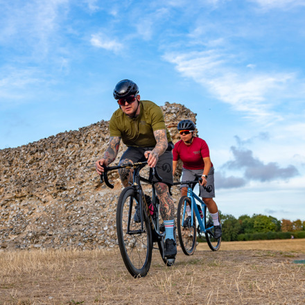 man and woman in gravel kit riding across a field