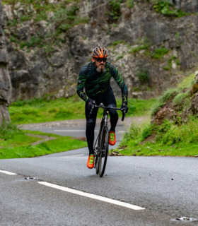 Man cycling up Cheddar Gorge wearing Pioneer jersey