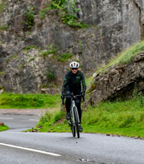 Woman riding her bike up Cheddar Gorge wearing Pioneer jersey